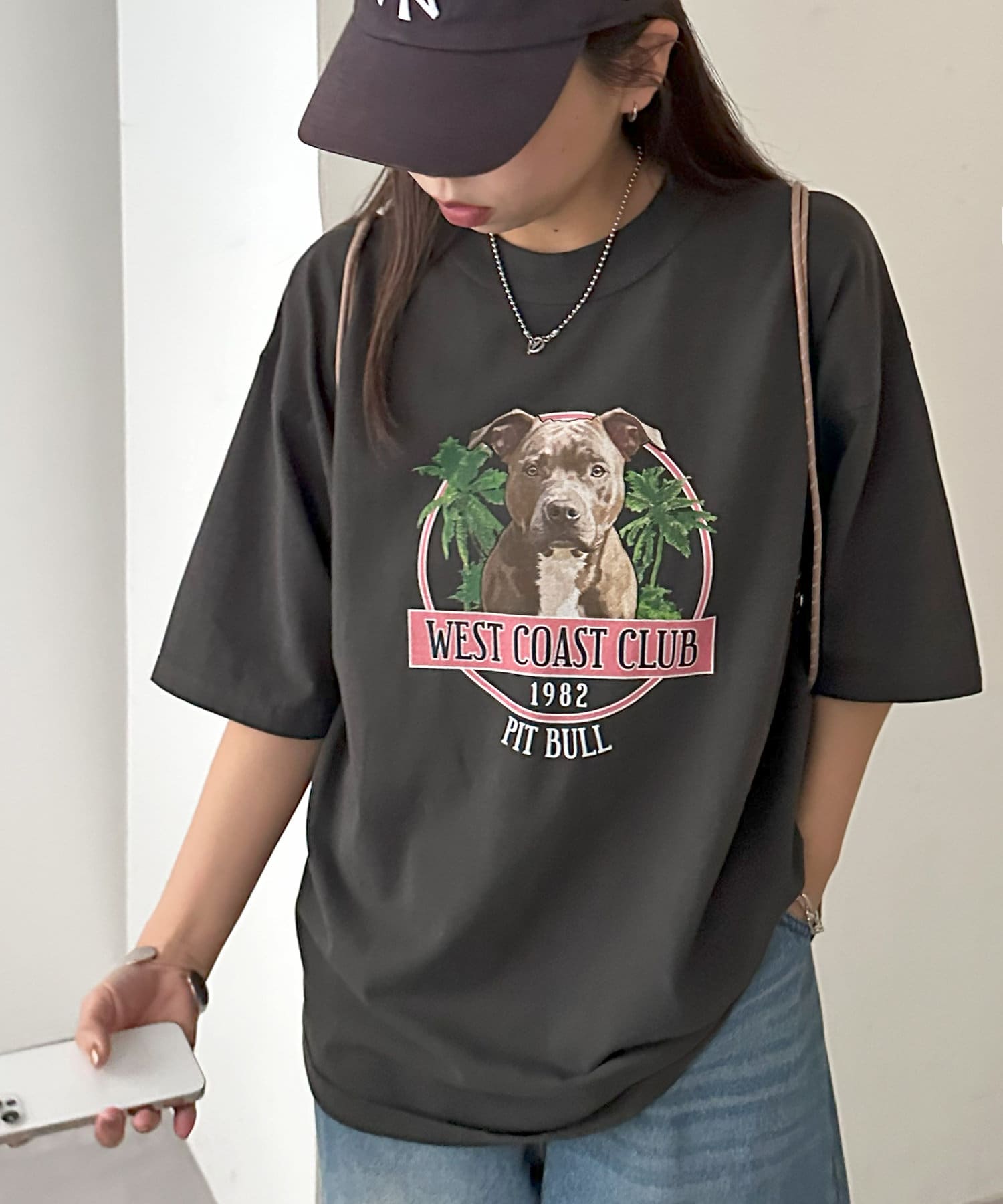 リゾート気分を感じる、遊び心たっぷりのドッググラフィックTシャツ●デザインフロントにヤシの木と愛らしい犬のイラストを施し、キャッチーながらもどこかヴィンテージ感漂う雰囲気が魅力。バックにもロゴデザイン